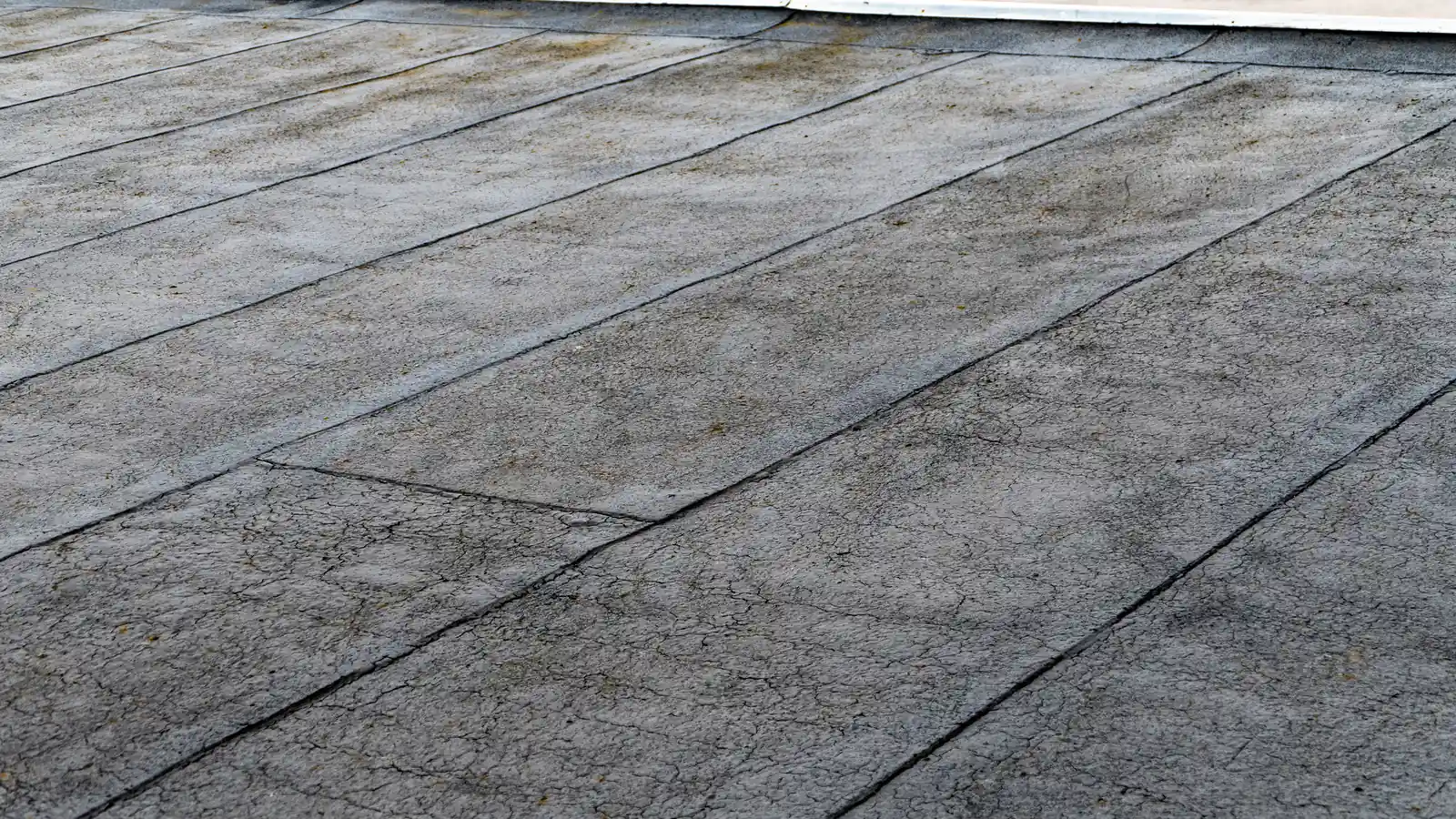 A flat roof covered in overlapping sheets of bituminous roll roofing, the asphalt-based family that includes modified bitumen