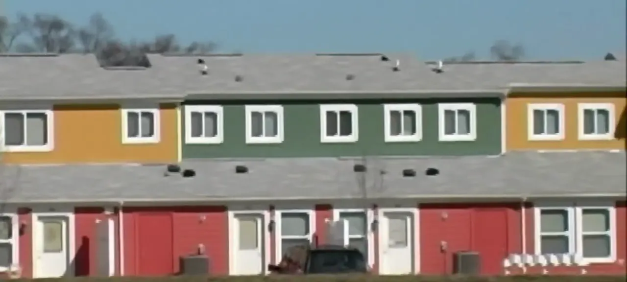 A row of two-story townhouses with fiber cement lap siding painted red, orange and green, with white window trim